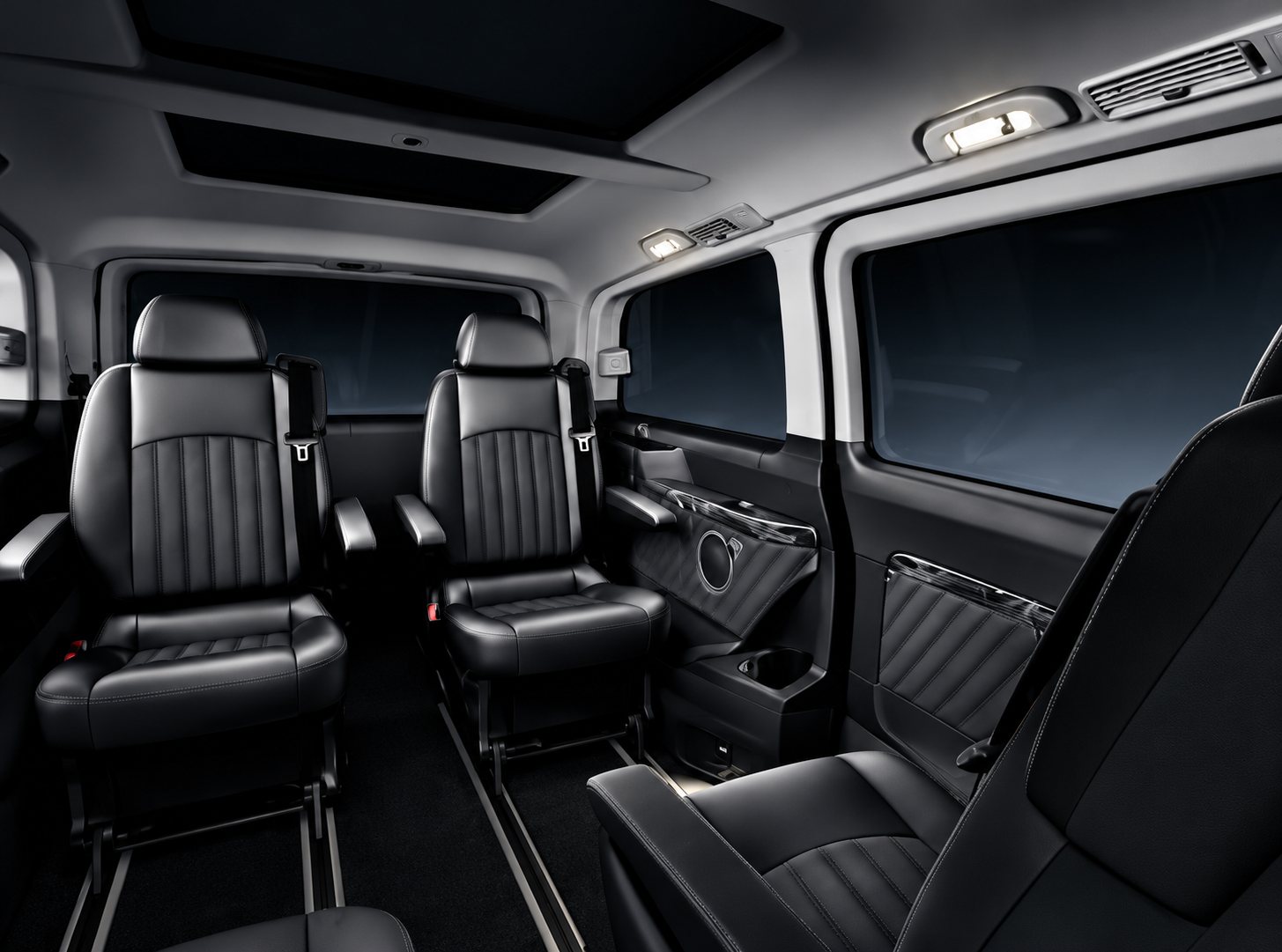 Intérieur d'un monospace de luxe aux sièges en cuir noir capitonné, avec panneaux de portes assortis et éclairage tamisé.